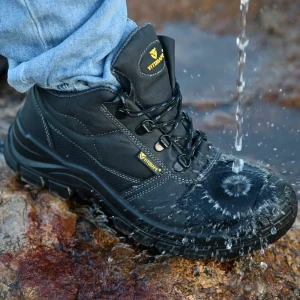 Black waterproof hiking boots being tested with running water, showing water droplets repelling off the surface.